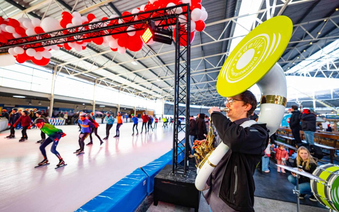De sousafonist van Redelijk Onverantwoord speelt zijn sola aan de rand van de ijsbaan, waar hard wordt geschaatst.