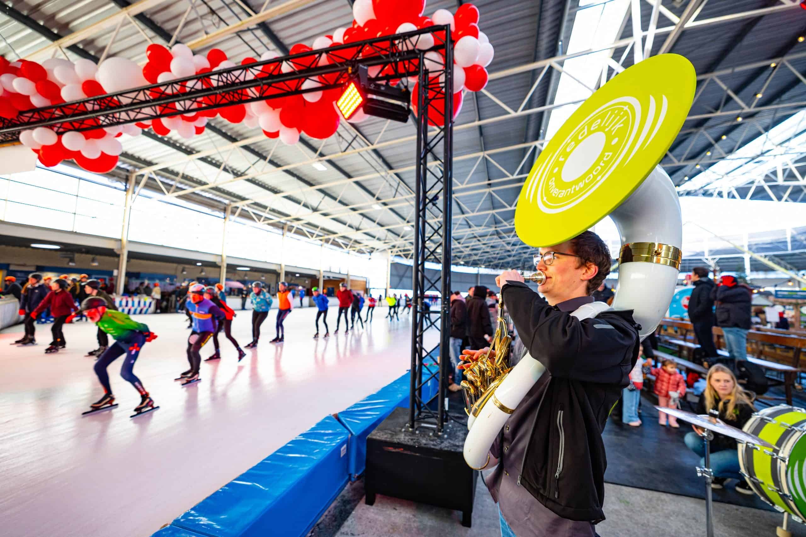 De sousafonist van Redelijk Onverantwoord speelt zijn sola aan de rand van de ijsbaan, waar hard wordt geschaatst.